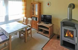 a living room with a fireplace and a table and a stove at 2 Bedroom Cozy Home In Boitzenburger Land in Rosenow
