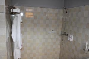 a bathroom with a shower with a white robe at ESCAPE VILLAGE HOTEL in Yumbe
