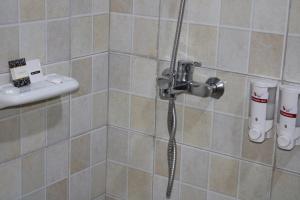 a shower with a hose in a tiled bathroom at ESCAPE VILLAGE HOTEL in Yumbe