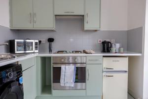 a kitchen with white cabinets and a stove top oven at GuestReady - Apt perto do centro da cidade in Liverpool