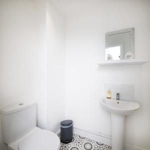a white bathroom with a toilet and a sink at GuestReady - Monochromatic Retreat in Liverpool