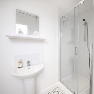 a white bathroom with a sink and a shower at GuestReady - Monochromatic Retreat in Liverpool