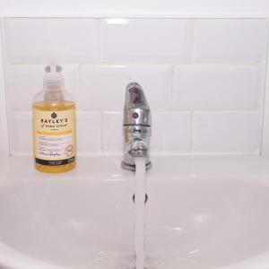 a bathroom sink with a bottle of soap next to a faucet at GuestReady - Monochromatic Retreat in Liverpool