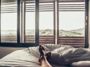 una persona sdraiata su un letto con i piedi su una coperta di Christiana Lodge a Plettenberg Bay