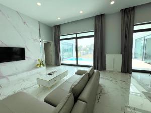 sala de estar con sofá y TV en 芭提雅湖景泳池别墅2, en Nong Prue
