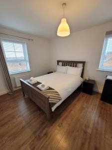 a bedroom with a bed and two windows at Skylark Apartment in Peacehaven