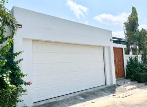 una puerta de garaje blanca frente a una casa en 芭提雅湖景泳池别墅2, en Nong Prue