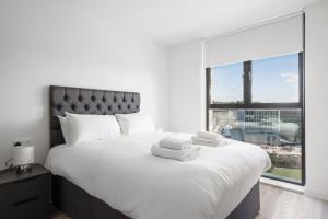 een slaapkamer met een groot wit bed en een groot raam bij GuestReady - Comforting city retreat in Vauxhall in Liverpool