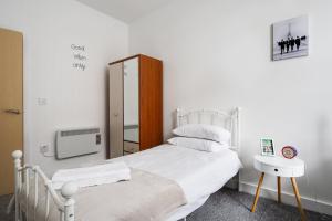 a bedroom with a white bed and a tv at GuestReady - One modern and calm city refuge in Liverpool