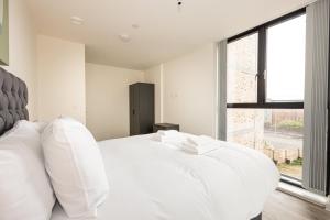um quarto branco com uma cama grande e almofadas brancas em GuestReady - Escapadela de luxo em Liverpool em Liverpool