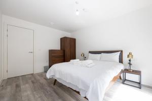 um quarto branco com uma cama branca e piso em madeira em GuestReady - Charm and Comfort in Vauxhall em Liverpool