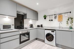 a kitchen with white cabinets and a washer and dryer at GuestReady - Charming Hideaway in Liverpool in Liverpool