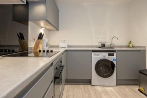 a white kitchen with a washing machine in it at GuestReady - Liverpool Adventure near World Museum in Liverpool