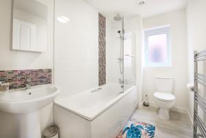 baño blanco con bañera y aseo en GuestReady - Humble Abode by Anfield Stadium en Liverpool