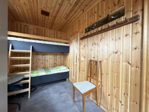 Historic wilderness cabin near Tystberga في Tystberga: غرفة صغيرة مع سرير بطابقين وكرسي