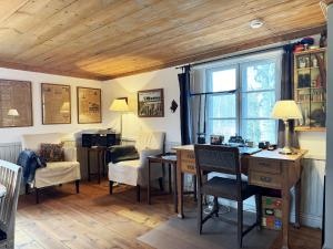 Historic wilderness cabin near Tystberga في Tystberga: غرفة بها مكتب وكراسي ونافذة