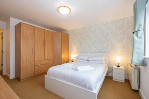 1 dormitorio con cama blanca y armarios de madera en GuestReady - Modern retreat in Liverpool en Liverpool