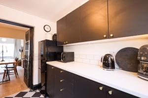 a kitchen with black cabinets and a black refrigerator at GuestReady - Walton's Delight in Liverpool