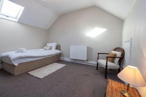 a bedroom with a bed and a chair at GuestReady - Walton's Delight in Liverpool