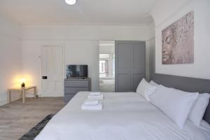 een wit bed in een kamer met een televisie bij GuestReady - A monochrome home in Anfield in Liverpool