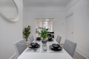 a white dining room with a table and chairs at GuestReady - A monochrome home in Anfield in Liverpool