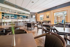 a restaurant with tables and chairs and a bar at Airways Hotels Frankfurt Airport West in Raunheim