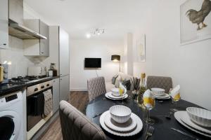 a kitchen with a table and chairs and a kitchen with a stove at Livestay Affordable Studio/1Bed Apartments in E14 in London