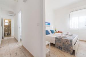 ein weißes Schlafzimmer mit einem Bett und einem Tisch in der Unterkunft Edoné, Wohnung mit Blick auf einen Sandstrand in Santa Maria Del Focallo