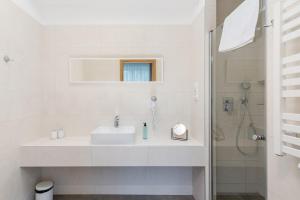 a white bathroom with a sink and a shower at Hotel Łaziska in Czchów