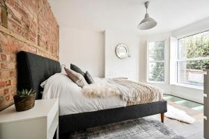 a bedroom with a bed and a brick wall at The Perfect Retreat-3 bedroom garden with Hot Tub in London