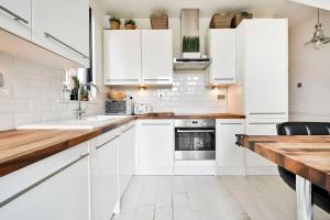 a kitchen with white cabinets and a wooden counter top at The Perfect Retreat-3 bedroom garden with Hot Tub in London