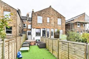 a backyard with a wooden fence and a table and chairs at The Perfect Retreat-3 bedroom garden with Hot Tub in London