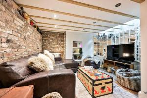 a living room with leather furniture and a brick wall at The Perfect Retreat-3 bedroom garden with Hot Tub in London