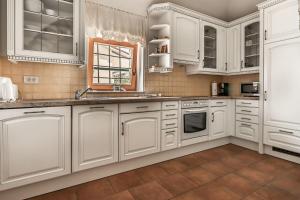 a white kitchen with white cabinets and a window at Pool Villa Lavanda in Šmarje