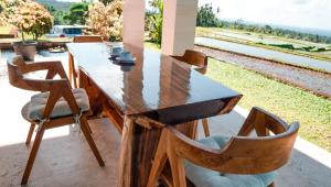 una mesa de madera y sillas con vistas a un tren en Dragonfly Cottage - 2Br Villa Jatiluwih, en Tabanan