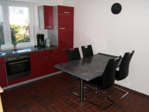 eine Küche mit roten Schränken sowie einem Tisch und Stühlen in der Unterkunft "Friesenhörn" 31 Merchant in Horumersiel