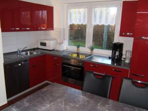 a kitchen with red cabinets and a sink at "Friesenhörn" 31 Merchant in Horumersiel