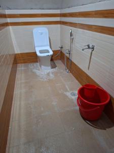 a bathroom with a toilet and a red bucket at Haveli Resort in Rishīkesh