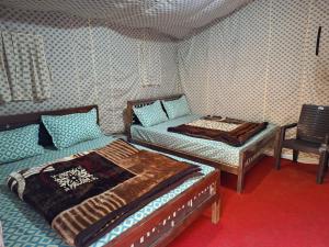 a bedroom with two beds and a chair in it at Haveli Resort in Rishīkesh