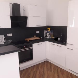 una cocina con armarios blancos y electrodomésticos negros en Delta Haus en Gelsenkirchen