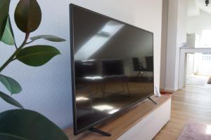 a flat screen tv sitting on a stand in a living room at Natur & Ruhe, neu & zentral, im Herzen von Freudenstadt in Freudenstadt