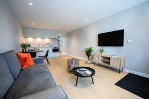 a living room with a gray couch and a kitchen at Hotel Royal in Noordwijk