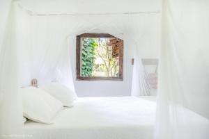 a bedroom with a white bed with a window at Casas da Lia in Trancoso