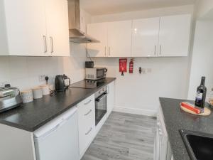 a kitchen with white cabinets and a black counter top at Lavender Cottage in Alnwick