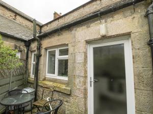 a patio with a table and chairs next to a building at Lavender Cottage in Alnwick