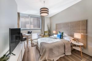 um quarto com uma cama, uma secretária e uma televisão em N20 Residence by Homenhancement em Genebra