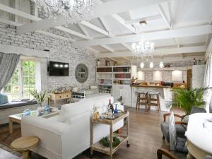 Elle comprend un salon doté d'un mobilier blanc et d'un mur en pierre. dans l'établissement Rose and Ivy Cottages, à Louis Trichardt