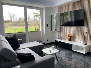 a living room with a couch and a flat screen tv at Apartament Łąkowa z tarasem in Brodnica