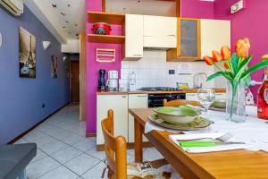 a kitchen with pink walls and a table with a vase of flowers at Magnolia Sirmione - Happy Rentals in Sirmione