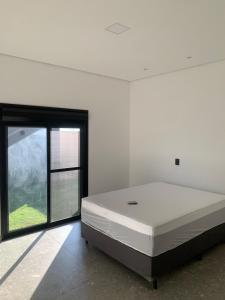 a white room with a large bed and a window at Casa de Campo Resort em Pardinho (Piscina c/ Borda Infinita) in Pardinho